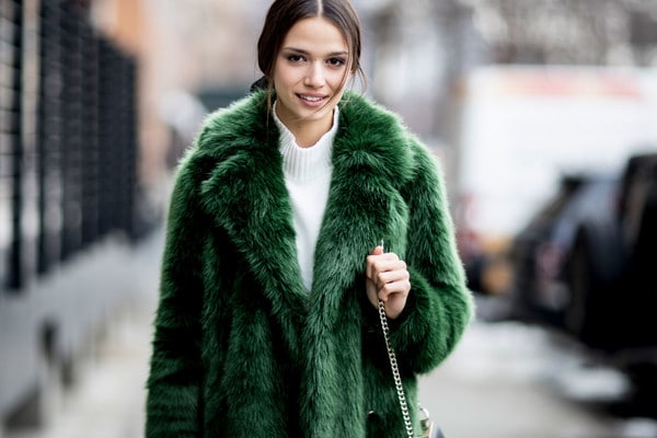 A brunette woman wearing a green fur coat