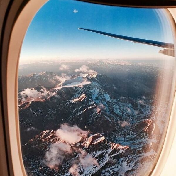 Affordable Luxury Travel - airplane window seat with mountains below